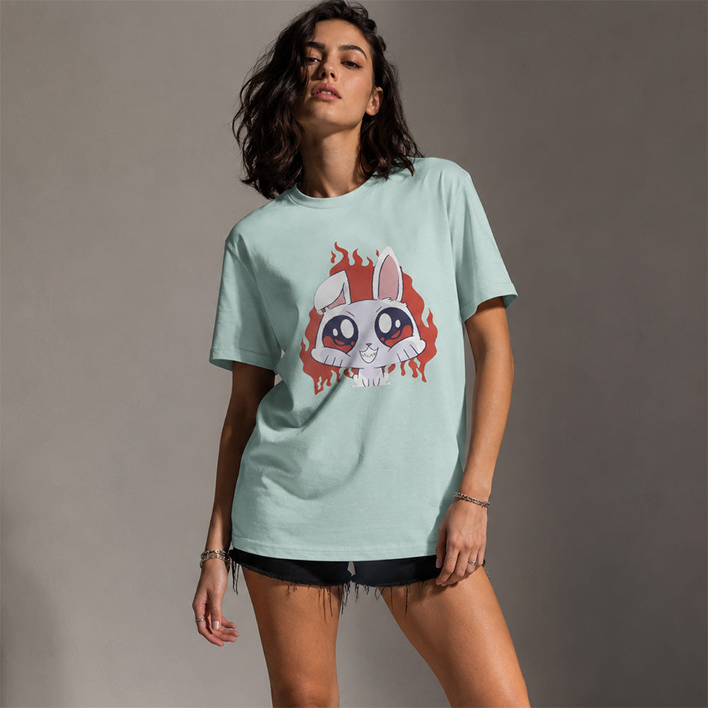 A woman modeling a light mint green t-shirt with a graphic of a white rabbit with red hair on the front, paired with black denim shorts against a neutral gray studio background.