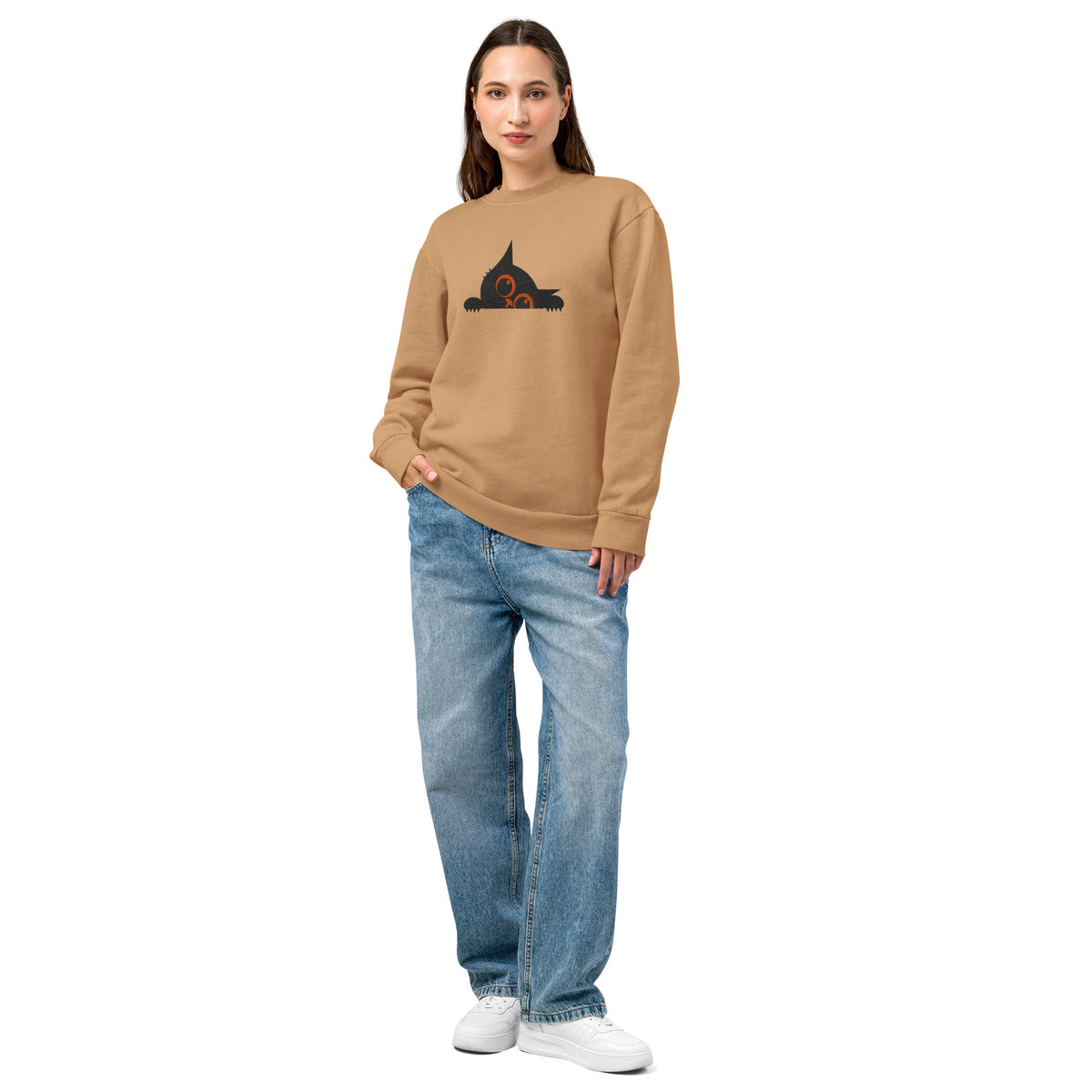 woman wearing a beige sweatshirt with a graphic design and blue jeans on a white background
