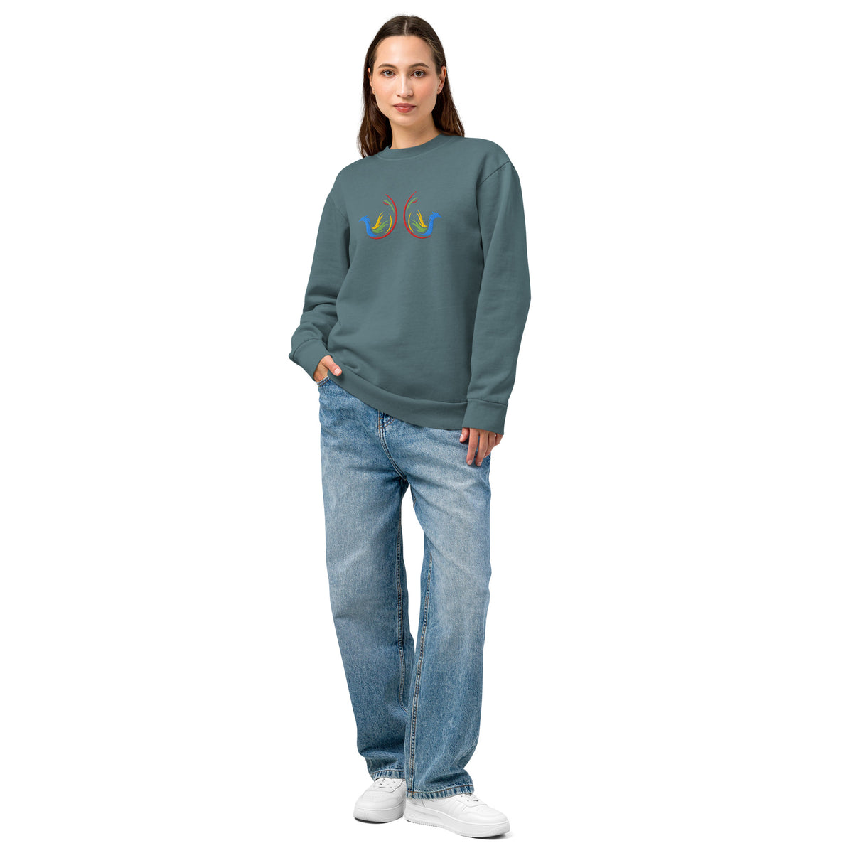 woman wearing a teal sweatshirt with a colorful logo and blue jeans on a white background