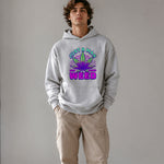 A man wearing a light gray pullover hoodie with a colorful graphic on the chest that reads 'JUST A MAN WEED' around a stylized cannabis leaf, paired with beige cargo pants, against a plain gray studio background.