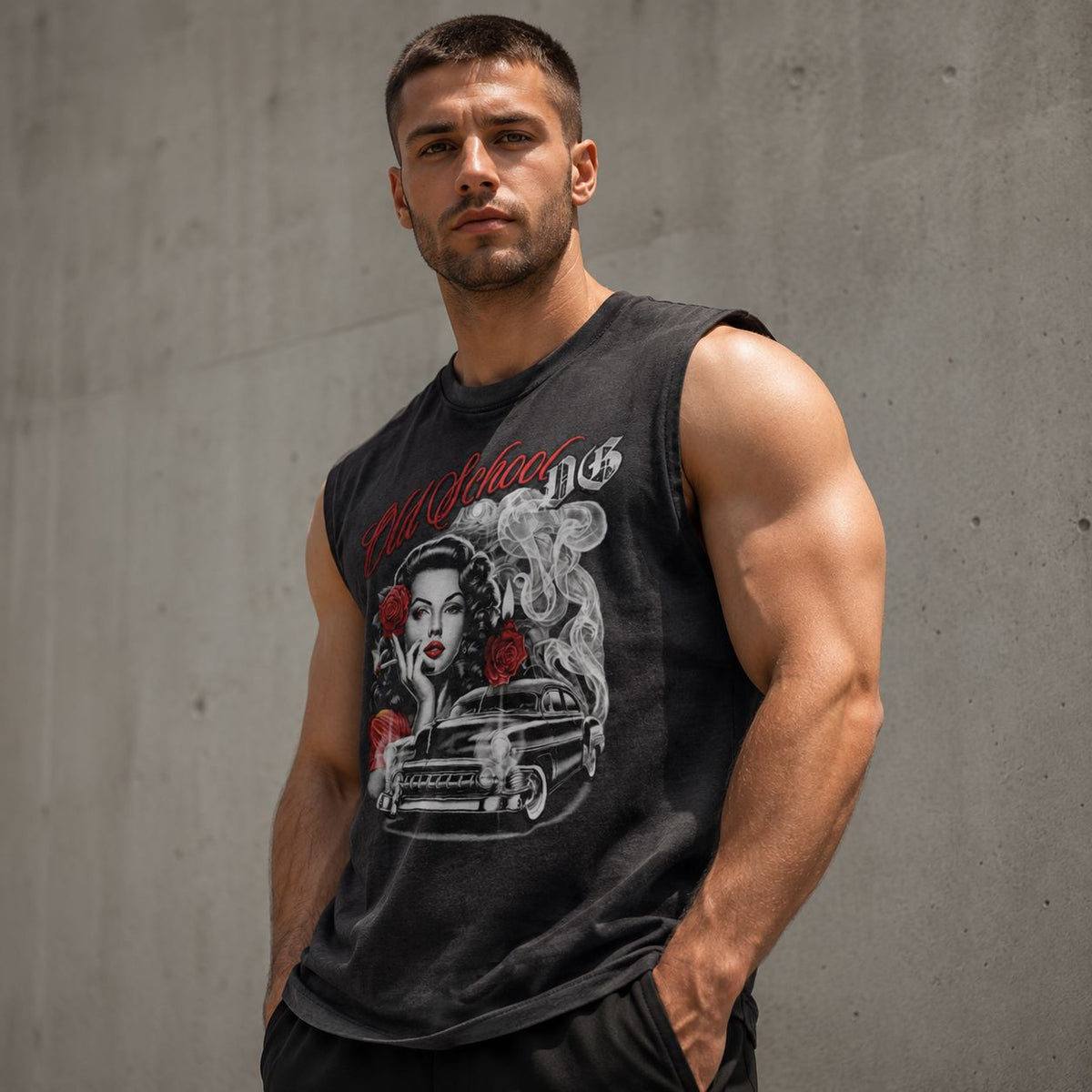 A muscular man wearing a black graphic sleeveless muscle tank top with a vintage pin-up woman and car design, standing against a gray concrete wall.