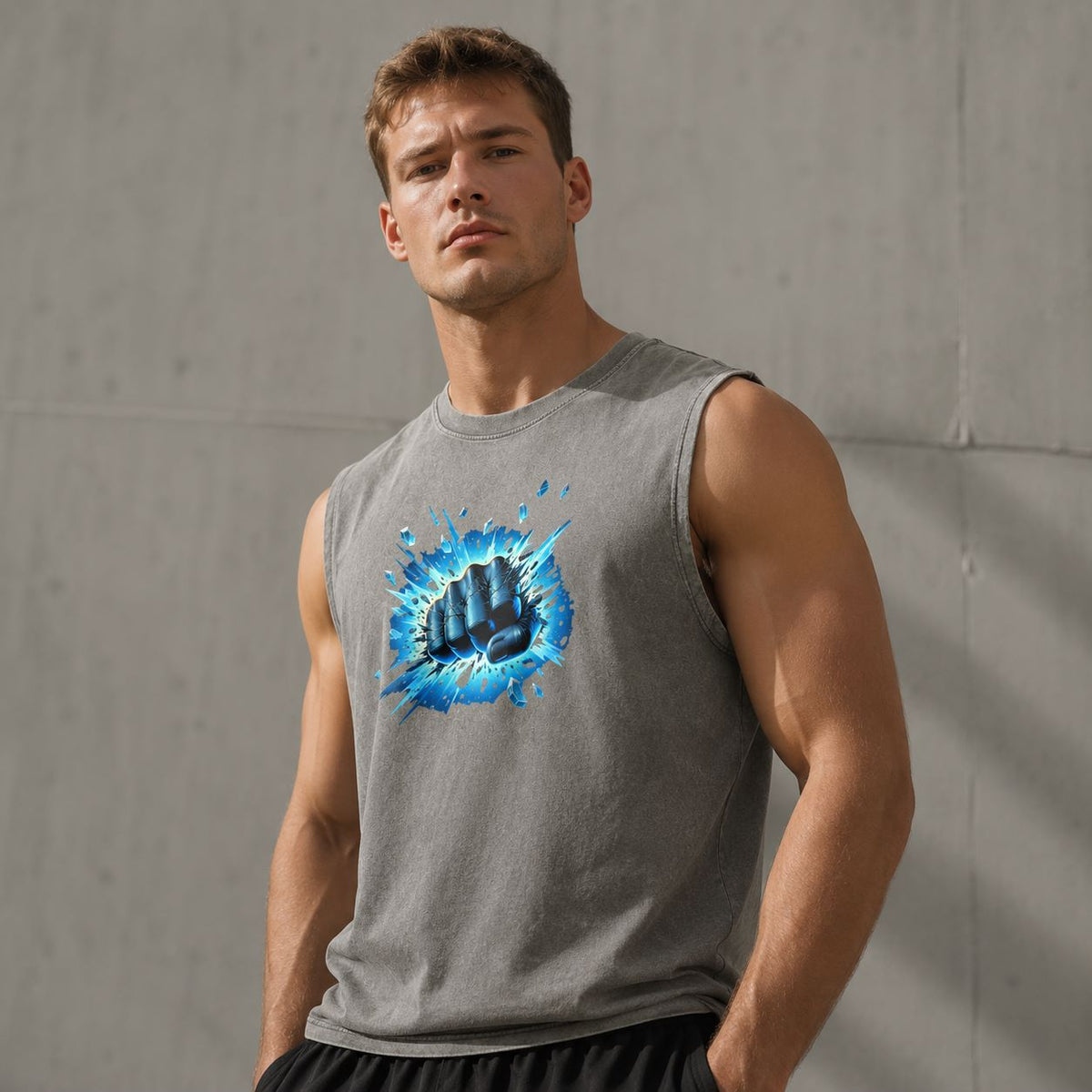 Man wearing a sleeveless gray shirt with a blue graphic design against a gray wall.