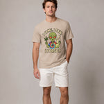 Man wearing a beige t-shirt with an alien graphic and text on a plain background