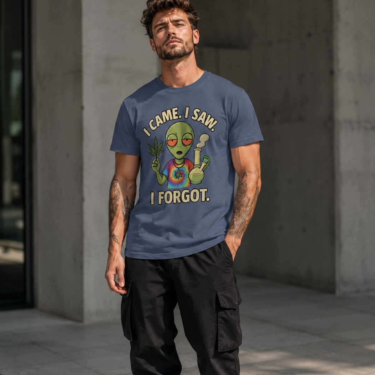 Man wearing a blue t-shirt with an alien graphic and text, standing against a concrete wall.