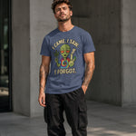 Man wearing a blue t-shirt with an alien graphic and text, standing against a concrete wall.