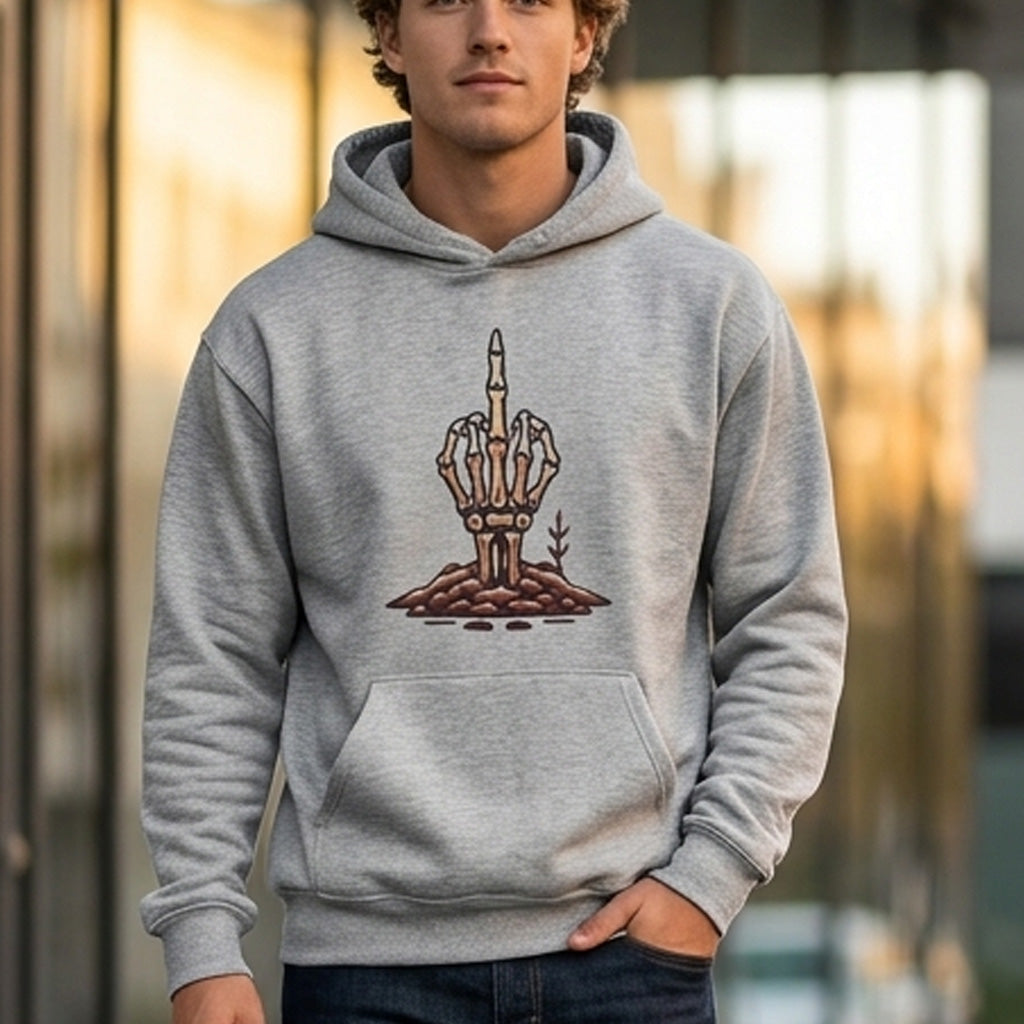 A young man wearing a gray hoodie with a graphic of a skeleton hand emerging from the ground and raising its middle finger, standing outdoors in an urban setting.