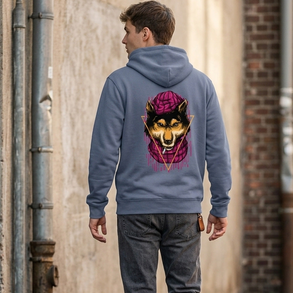 A person wearing a gray hoodie with a graphic of a wolf in a purple hat on the back stands in an alleyway, facing away from the camera. The alley has a brick wall and metal pipes.