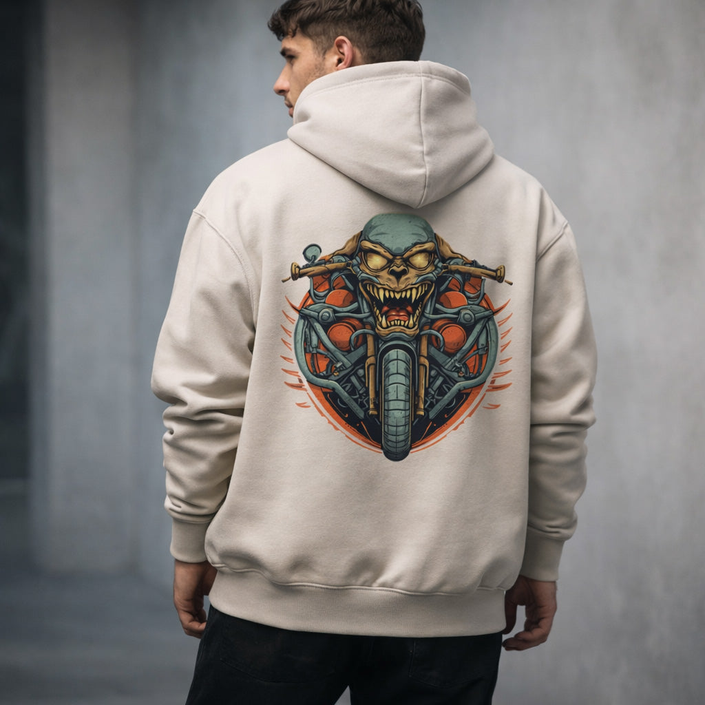 A person wearing a beige hoodie with a graphic on the back showing a snarling skull merged with a motorcycle, featuring handlebars and wheels, in a bold, edgy design.