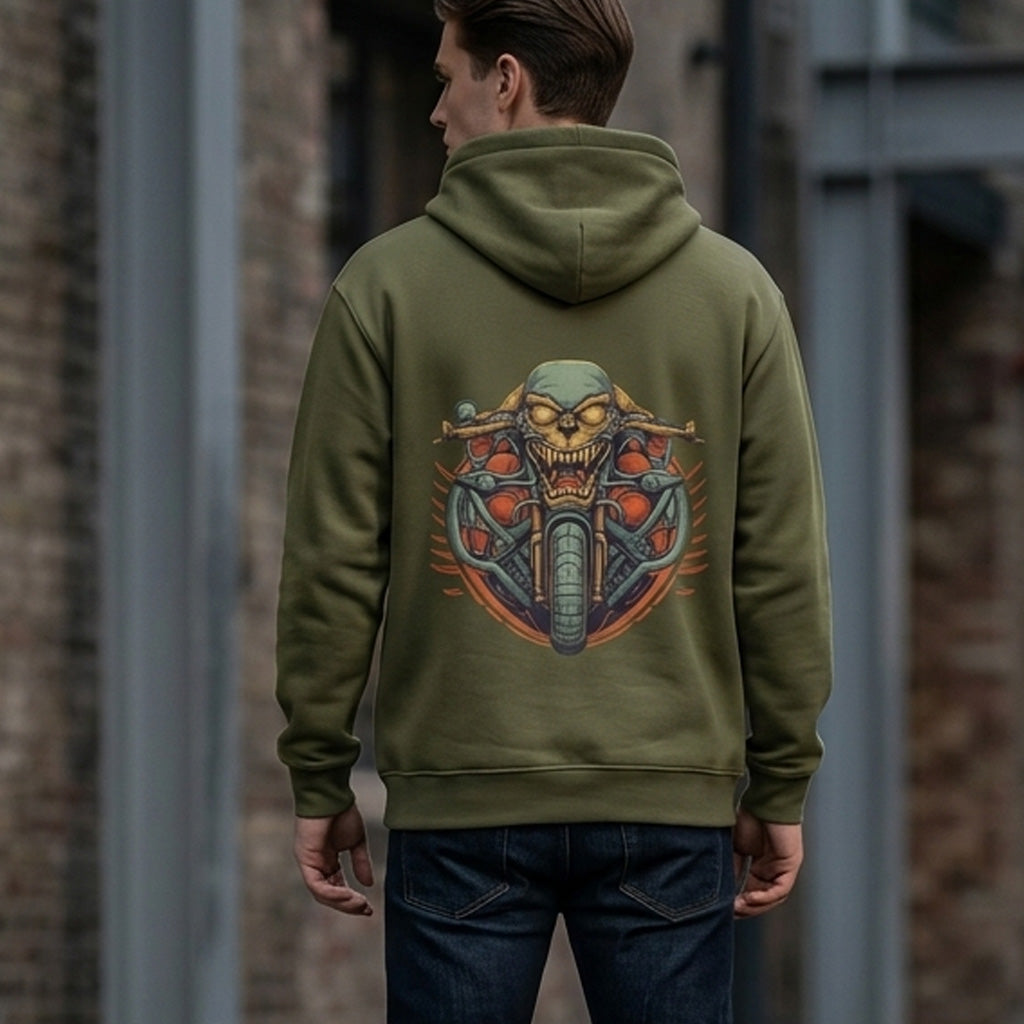 A person wearing an olive green hoodie with a colorful graphic of a menacing skull riding a motorcycle on the back, standing outdoors near a brick wall.