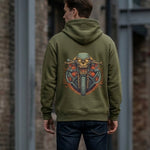 A person wearing an olive green hoodie with a colorful graphic of a menacing skull riding a motorcycle on the back, standing outdoors near a brick wall.