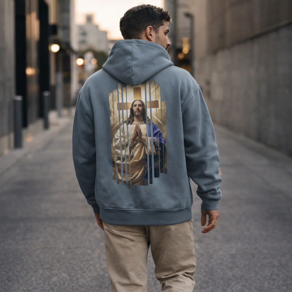 Person wearing a hoodie with a graphic of a religious figure on the back, walking down a city street.