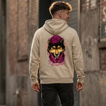 A man stands outdoors wearing a tan hoodie with a colorful graphic of a dog in a purple hood on the back. He faces away from the camera, walking along a brick and concrete building.
