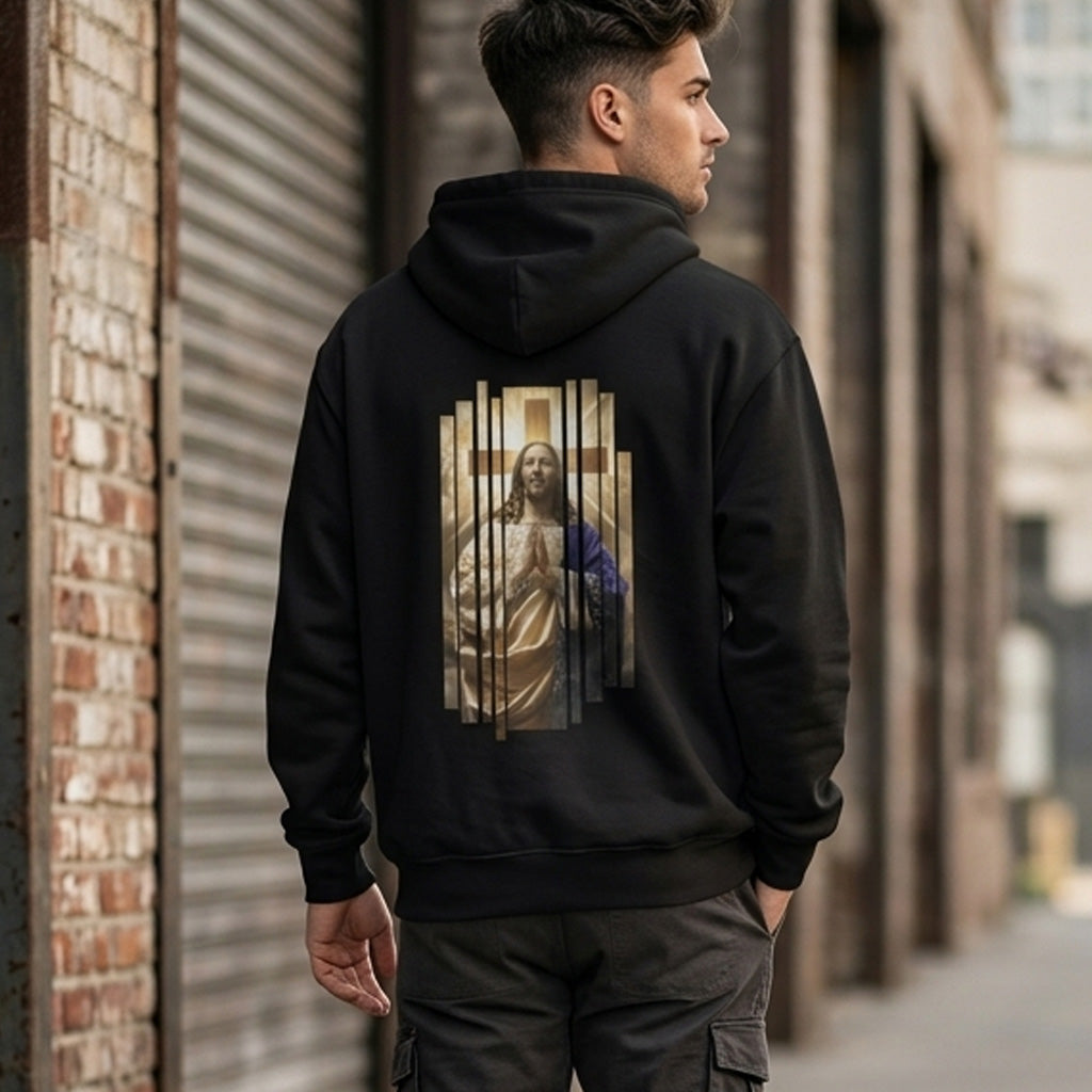 A man stands outdoors wearing a black hoodie with an artistic image of Jesus on the back, featuring vertical lines. He faces away from the camera in an urban setting with brick walls and metal shutters.
