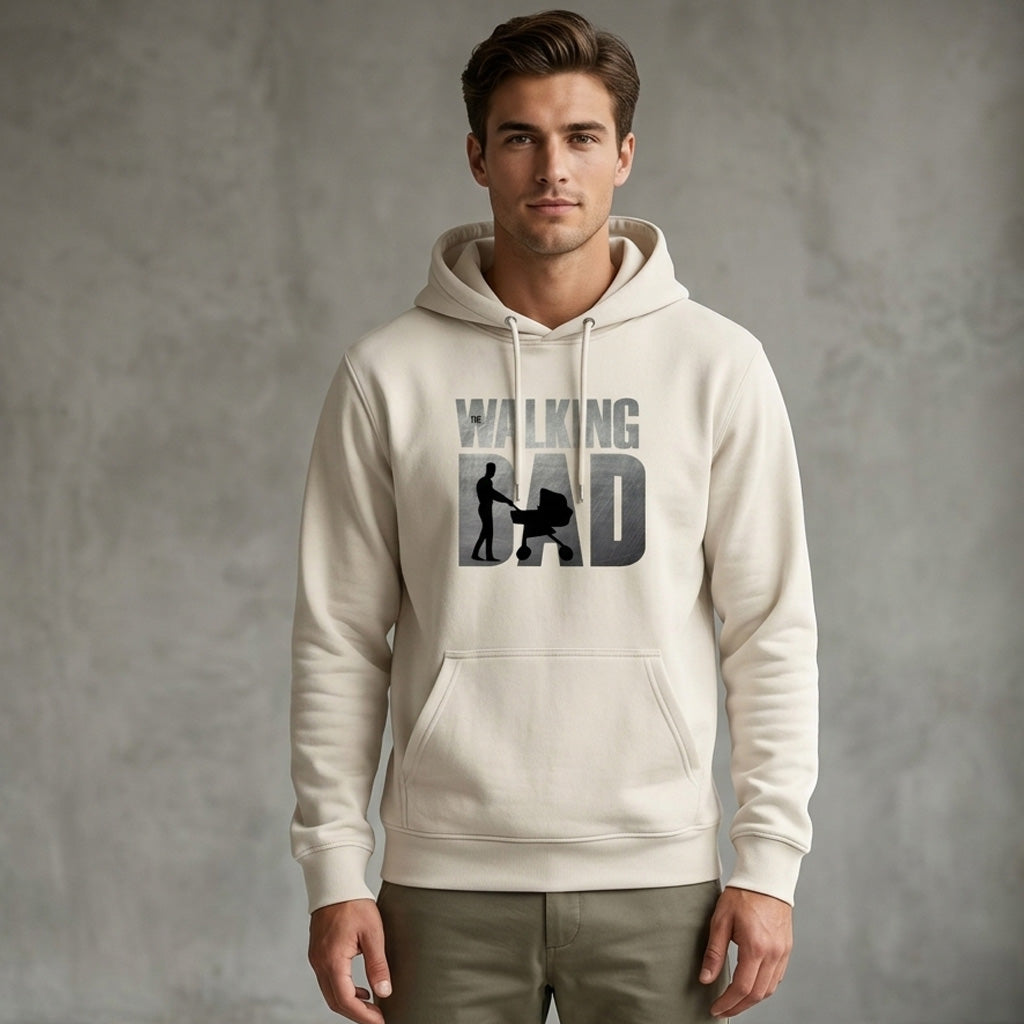 A man wearing a light-colored hoodie with the words "WALKING DAD" and an image of a man pushing a stroller printed on the front stands against a plain gray background.