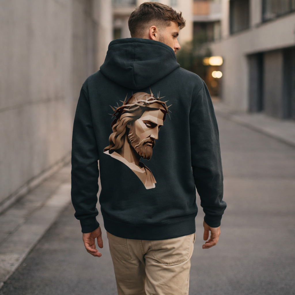 A man wearing a black hoodie with an illustrated image of Jesus wearing a crown of thorns on the back walks down an empty, modern urban street.