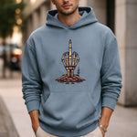 A man wearing a blue hoodie with a graphic of a skeleton hand rising from the ground and making a middle finger gesture stands outdoors on a city sidewalk.