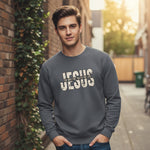 A young man stands in a sunlit alley wearing a gray sweatshirt with "JESUS The Way The Truth The Life" printed in bold letters on the front. Brick walls and green vines are visible in the background.