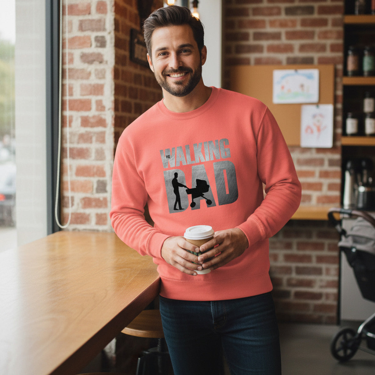 Man wearing a pink sweatshirt with 'WALKING BAD' text, holding a coffee cup in a casual setting.
