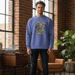 Man wearing a blue sweatshirt with an alien graphic and text in a room with brick walls and plants.