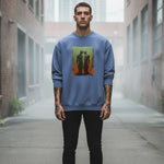 A man with tattoos stands in an urban alleyway, wearing a blue sweatshirt featuring abstract art of two figures. The background is misty with tall buildings visible in the distance.