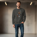A man in a dark sweatshirt with a graphic tiger claw mark design and blue jeans stands indoors, smiling, with blurred lights and a neutral background.