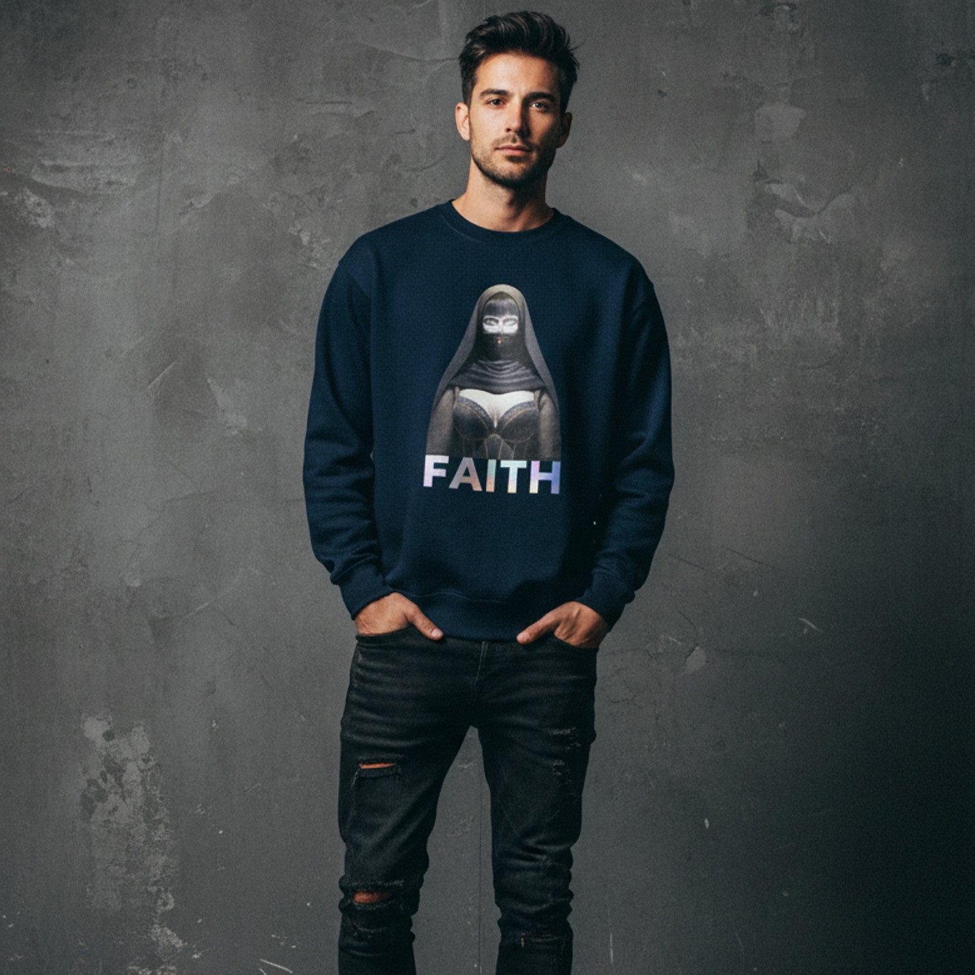 A man stands against a textured gray wall, wearing a navy blue sweatshirt featuring an illustrated woman in a headscarf with the word "FAITH" printed below the image. He has his hands in his pockets and wears ripped black jeans.