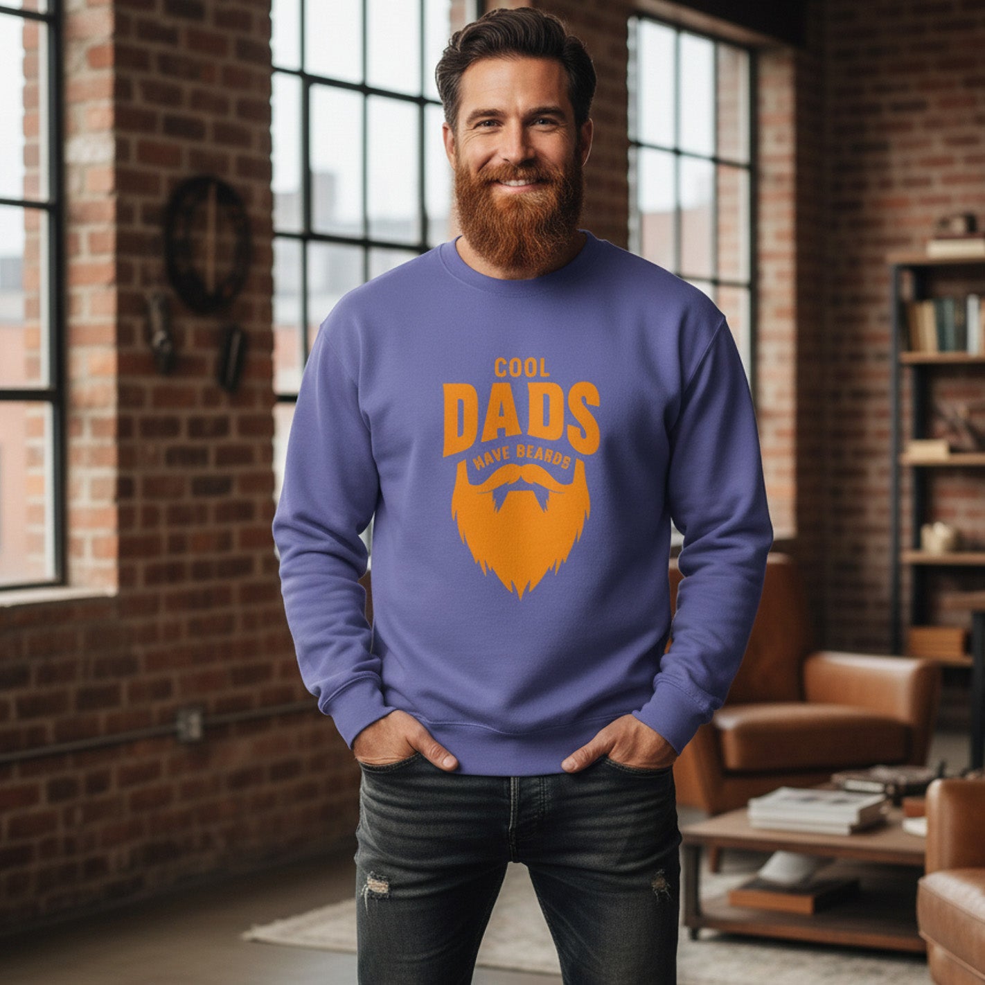 Man wearing a blue sweatshirt with orange text and beard graphic in a room with brick walls and large windows.