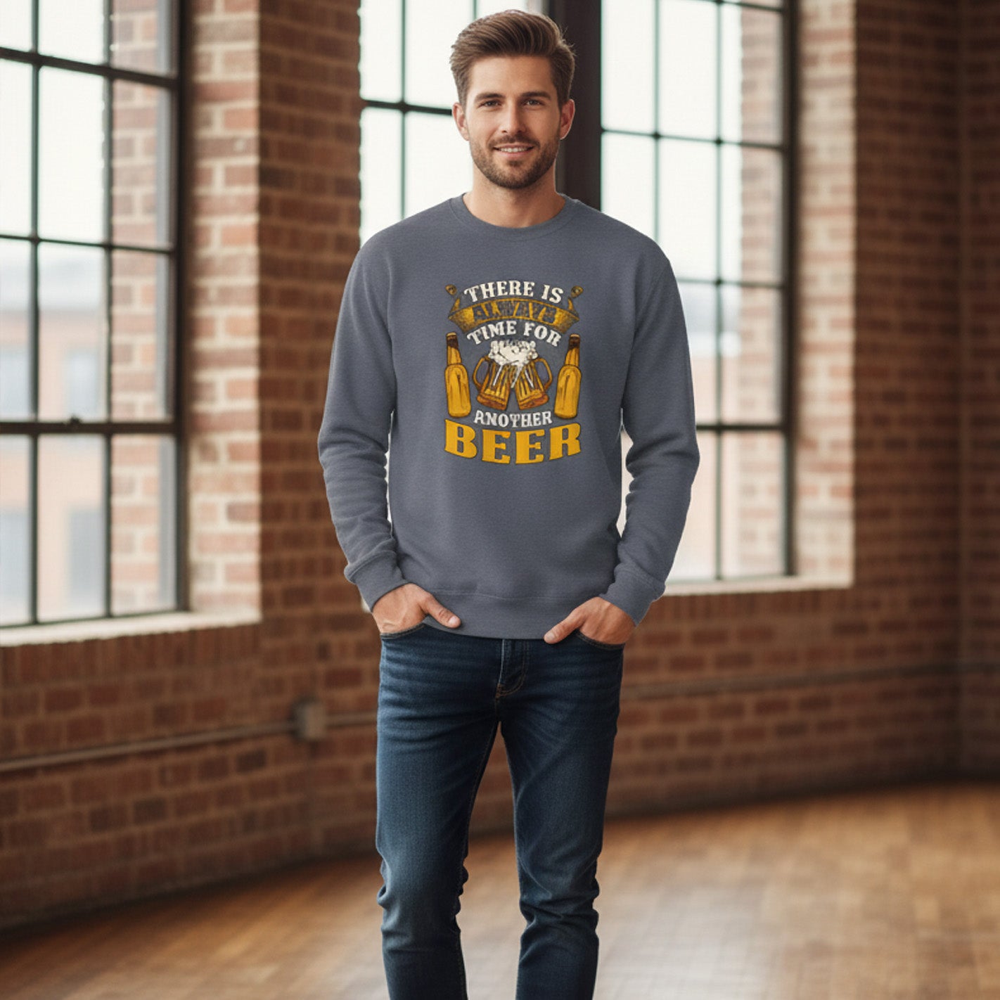 Man wearing a gray sweatshirt with a humorous beer graphic and text in a room with brick walls and large windows.