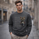 A young man stands outdoors wearing a sweatshirt that features a cartoon cat and the words "Life is Tough But The Mood is Great.