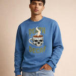 Man wearing a blue sweatshirt with a skull and coffee cup graphic and text.