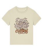 A light beige short-sleeve womens t-shirt with a retro-style graphic text print reading 'Don't give me something I can't wear in the evening' in brown and orange lettering with small star accents.