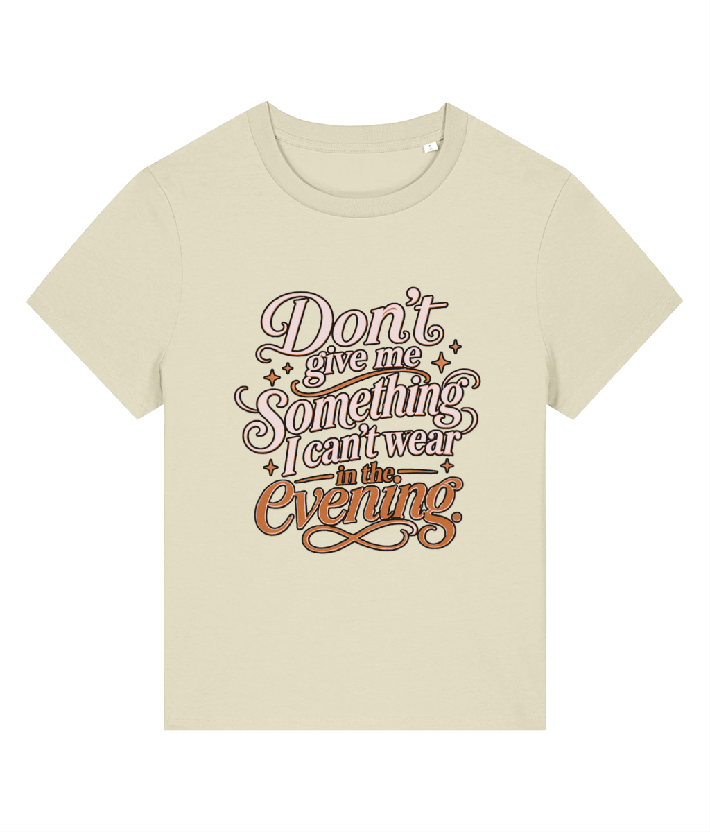 A light beige short-sleeve womens t-shirt with a retro-style graphic text print reading 'Don't give me something I can't wear in the evening' in brown and orange lettering with small star accents.