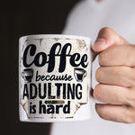 Mug with 'Coffee because adulting is hard' text held by a person