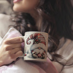 Woman holding a mug with a decorative design of a gnome.