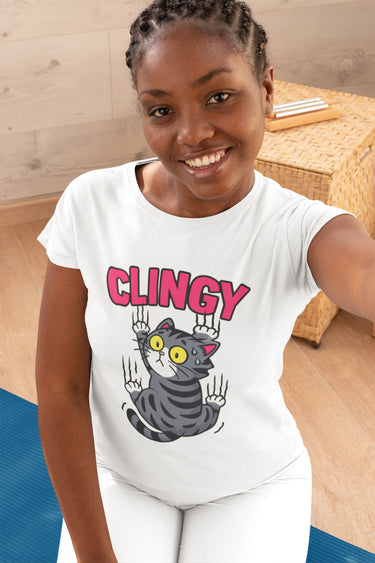 Person wearing a white t-shirt with a graphic design and text, sitting on a wooden floor.