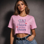 A woman wearing a pink crop top with the text "SEX is part of Nature and I love Nature" stands confidently with one hand on her hip, sporting high-waisted jeans, gold hoop earrings, and a chain necklace.