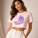 Woman wearing a pink crop top with a purple cat graphic and text on a plain background