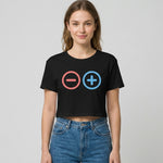 A woman wearing a black crop top with a red minus sign in a circle and a blue plus sign in a circle, standing against a plain, light-colored background.