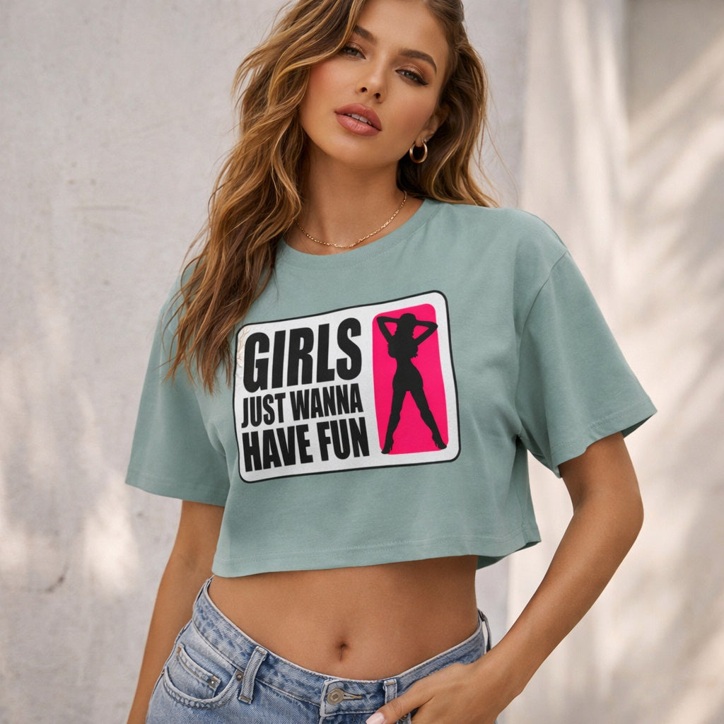 A woman in a green crop top and jeans stands confidently. Her shirt features a silhouette of a woman and the text "Girls Just Wanna Have Fun" in bold letters.