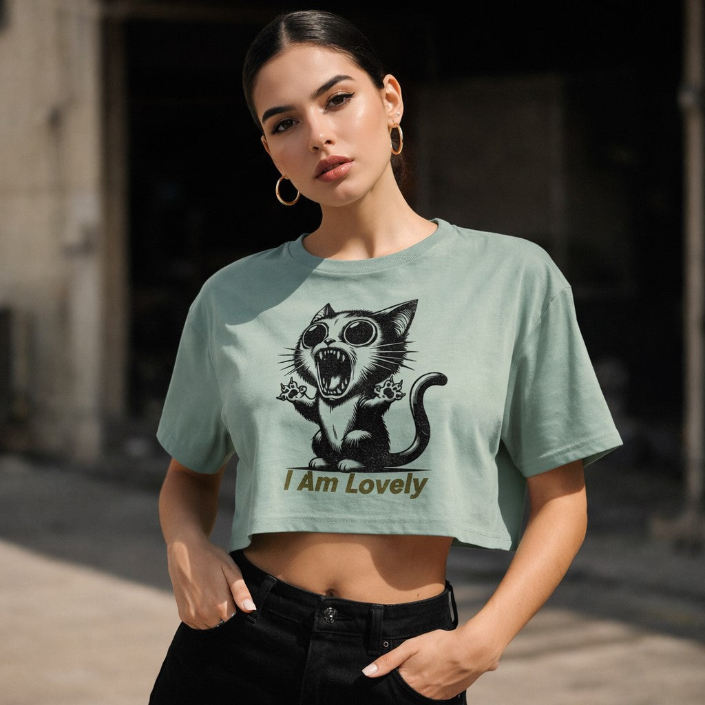 Woman wearing a light green crop t-shirt with a graphic of a cat and text 'I Am Lovely' outdoors.