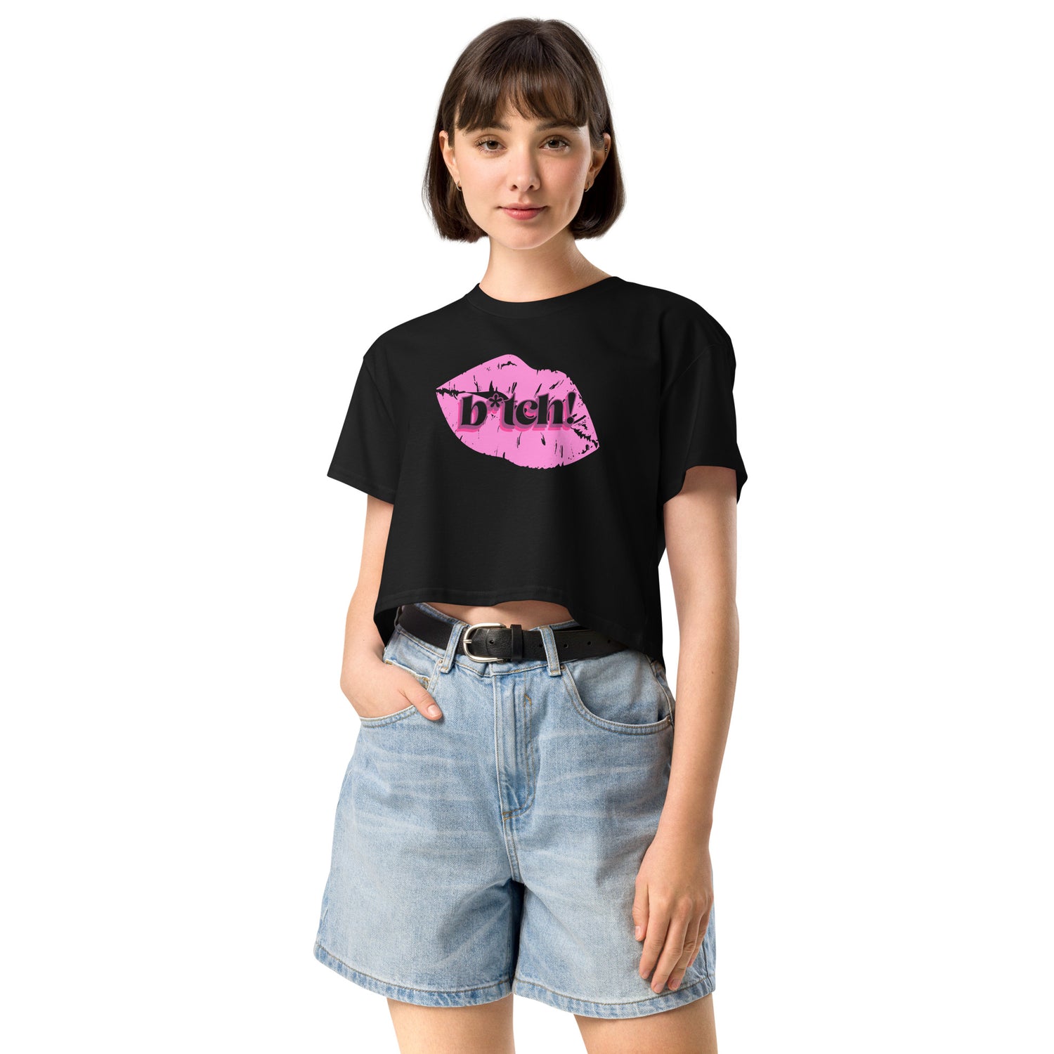 woman wearing a black crop t-shirt with pink graphic and denim shorts on a white background