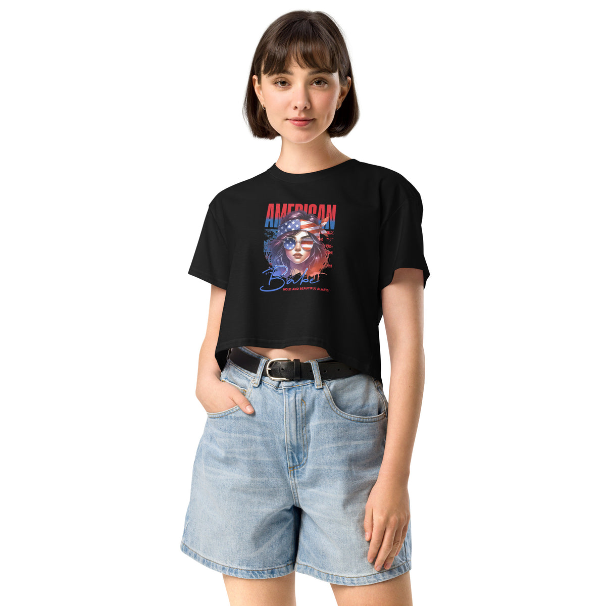 Woman wearing a black crop t-shirt with a graphic design and denim shorts on a white background