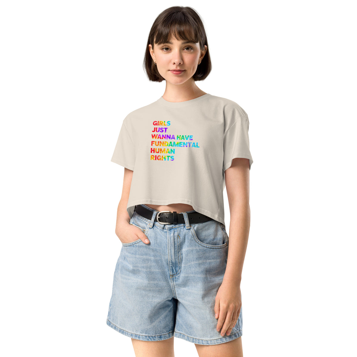 Woman wearing a beige t-shirt with colorful text and denim shorts on a white background