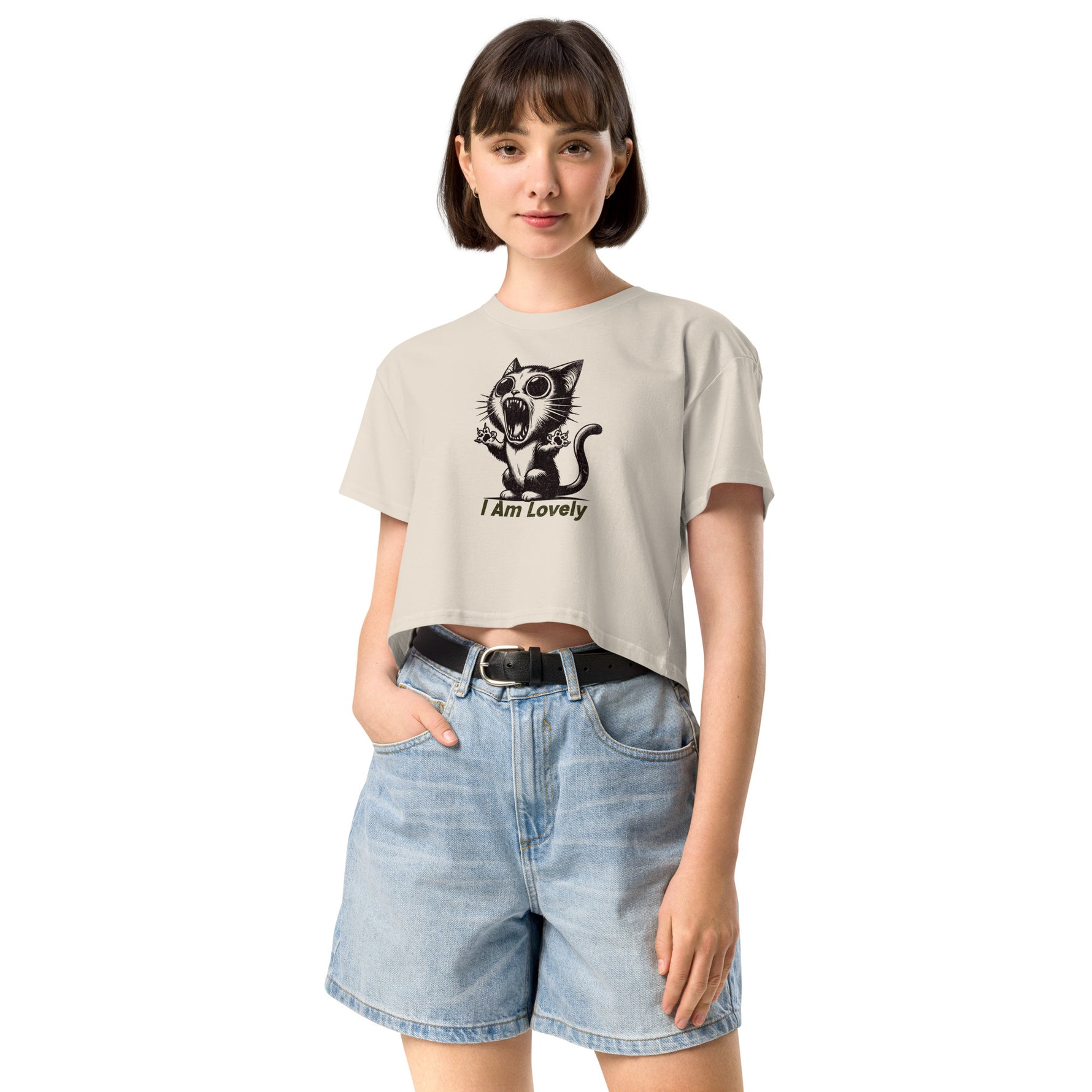 Woman wearing a beige crop t-shirt with a graphic design and text, paired with denim shorts on a white background.