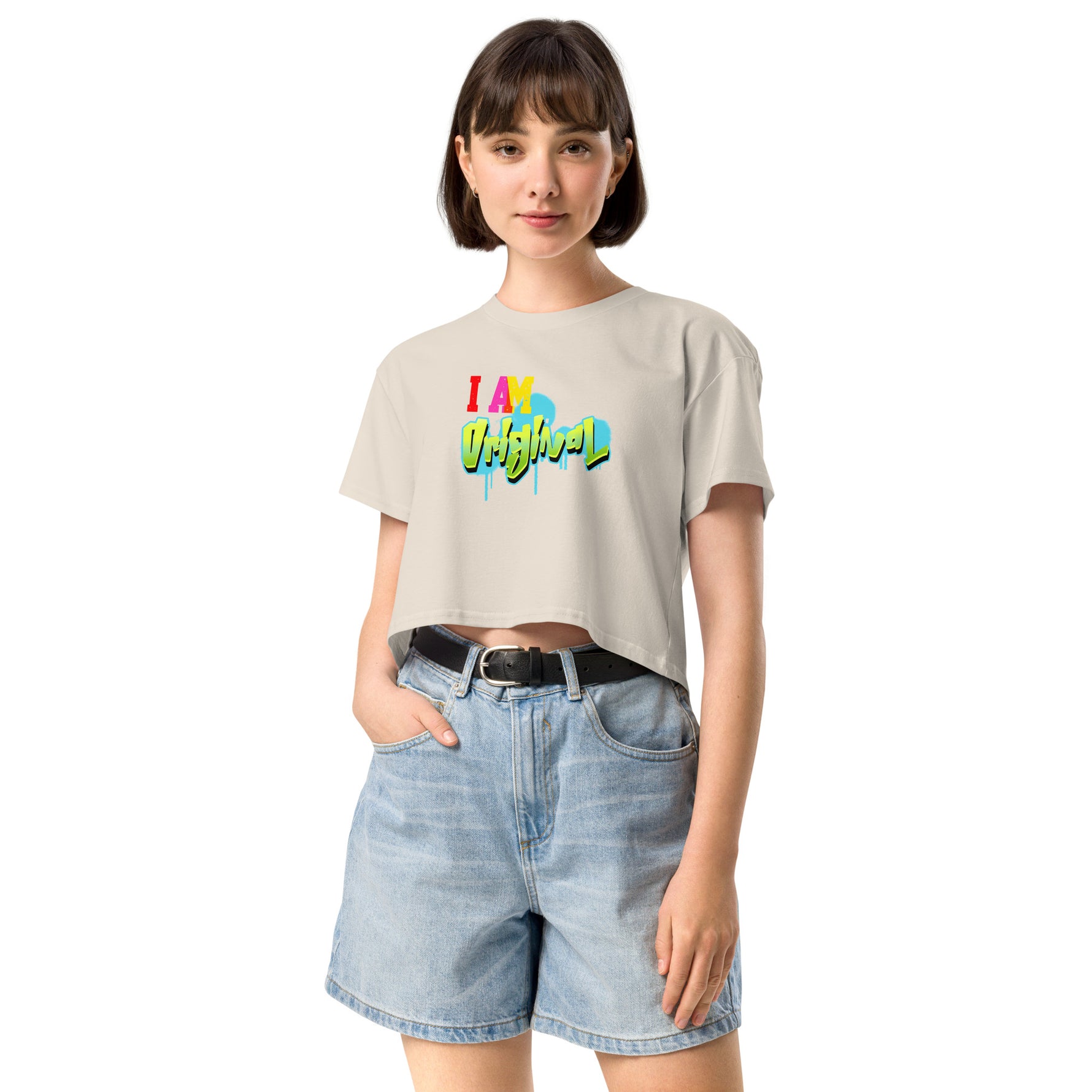 Woman wearing a beige crop t-shirt with colorful text and denim shorts on a white background