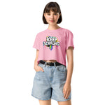 Woman wearing a pink t-shirt with 'Keep Scrolling' text and denim shorts on a white background