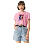 Woman wearing a pink crop t-shirt with a graphic design and denim shorts on a white background