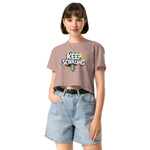 Woman wearing a beige t-shirt with 'Keep Scrolling' text and denim shorts on a white background