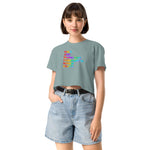 Woman wearing a light blue t-shirt with colorful text design and denim shorts on a white background