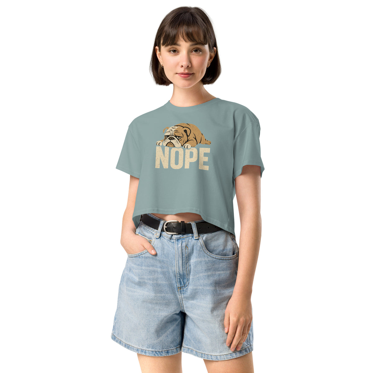 Woman wearing a light blue t-shirt with a dog graphic and 'NOPE' text, paired with denim shorts on a white background.